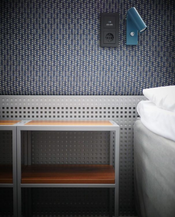 Hotellmöbler - blå sänggavel med lampa. Perforerad plåt elementskydd.